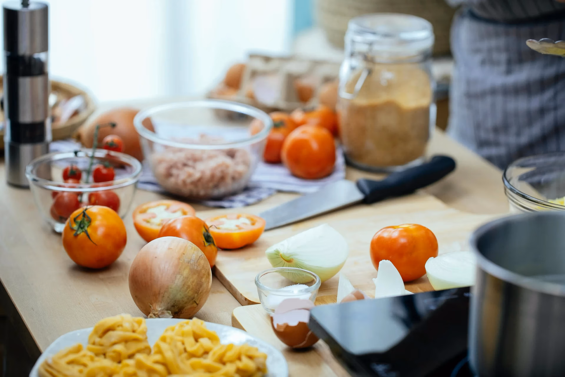 Kitchen table with healthy ingredients including raw onions, garlic, and tomatoes